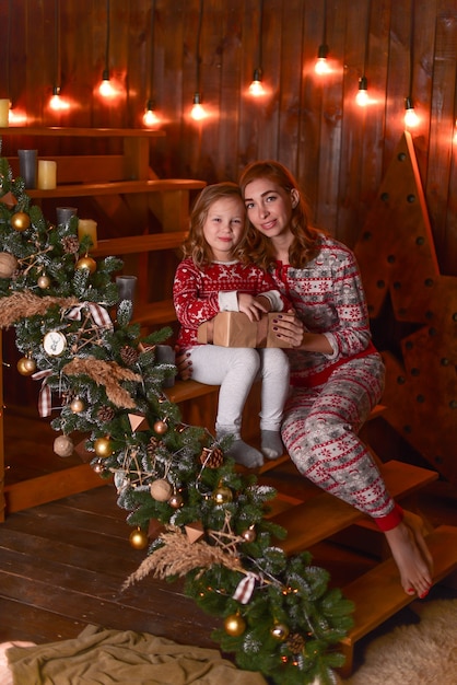 La madre y la hija sentadas en los escalones cerca de Navidad