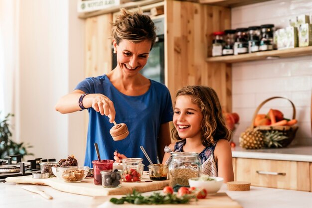 Foto madre y hija sonrientes preparando comida en la cocina de casa