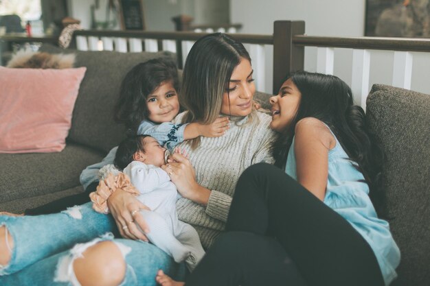 Madre con hijas sentadas en el sofá en casa