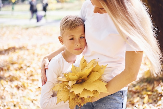 Madre con hijo descansar en un hermoso parque de otoño en un día soleado.