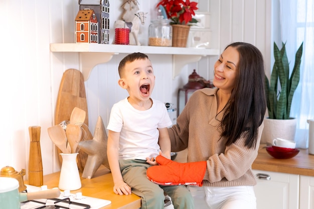 Madre y hijo divertidos jugando en la cocina felices pasando el tiempo en la víspera de Navidad y la víspera de Año Nuevo