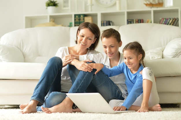 Madre con hijo e hija usando laptop