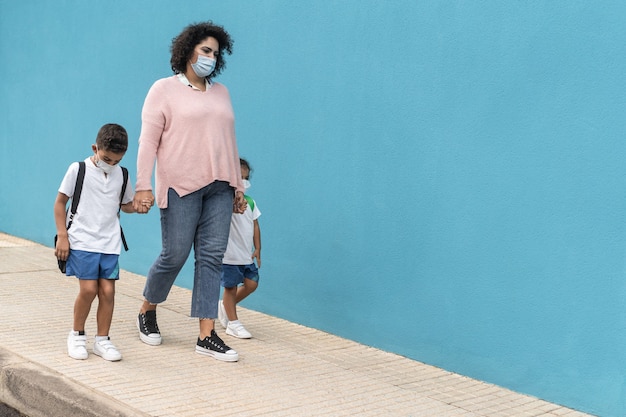 Madre con hijo e hija volviendo a la escuela con máscaras de seguridad - Centrarse en la cara de mamá