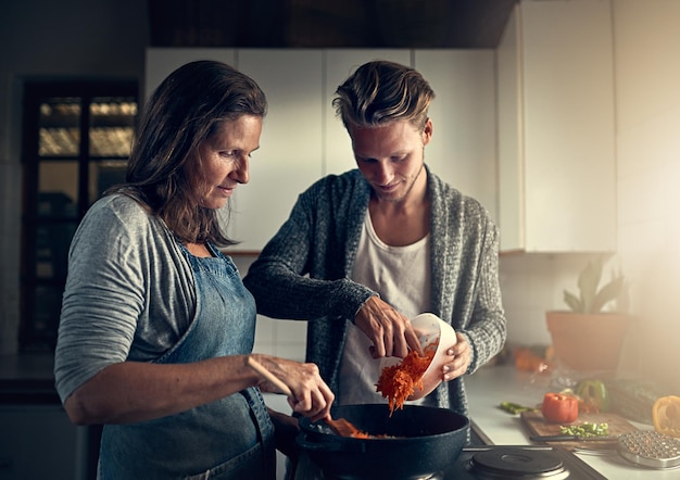 Madre y hijo maduros con verduras en la cocina para apoyar el vínculo o ayudar a cocinar la cena Mujer o hombre de la familia en el hogar con preparación para una comida saludable nutrición o hambre en la casa