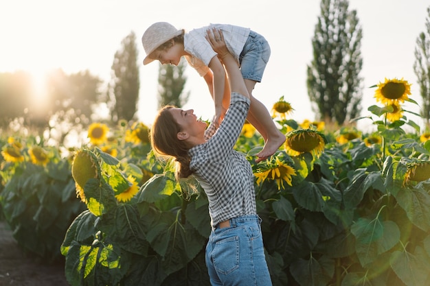 Madre con hijo pequeño en campo de girasoles durante la hora dorada, mamá e hijo están activos en la naturaleza