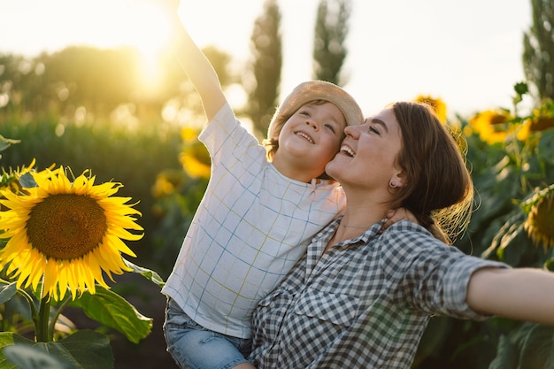 Madre con hijo pequeño en campo de girasoles durante la hora dorada, mamá e hijo están activos en la naturaleza