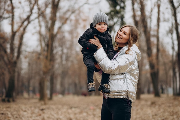 Madre con hijo pequeño juntos en el parque de otoño