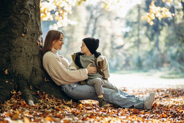 Madre con hijo pequeño en el parque sentado bajo el árbol