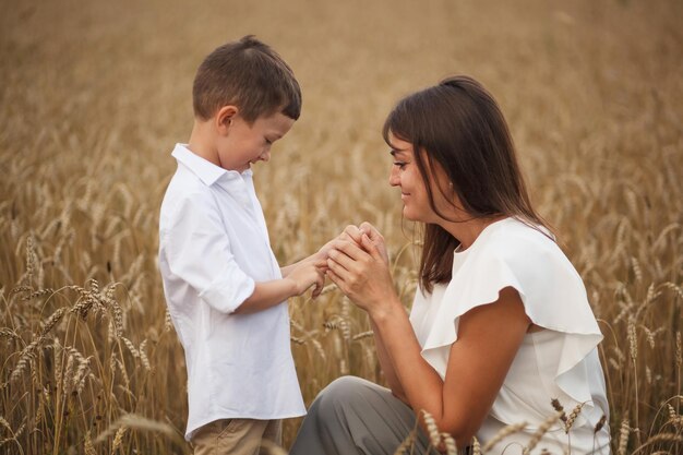 Madre con hijo sonriendo cogidos de la mano en un campo en verano Concepto de familia amistosa