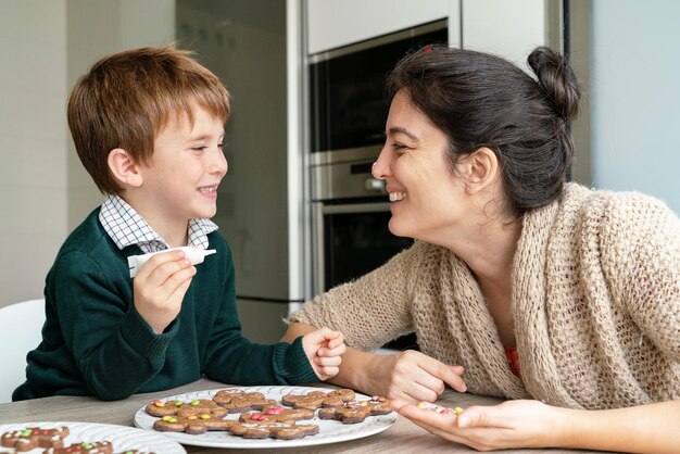 Foto madre y hijo sonrientes haciendo galletas en casa