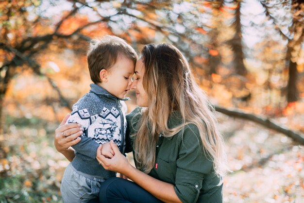 Madre con hijo de tres años en otoño el bosque, abrazo y ternura