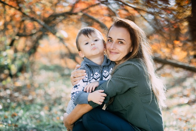 Madre con hijo de tres años en otoño el bosque, abrazo y ternura