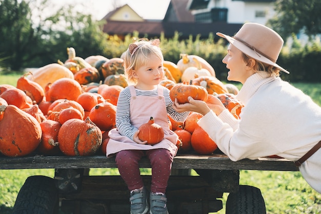 Madre con hijos están eligiendo calabaza en el mercado agrícola Concepto de otoño de familia feliz