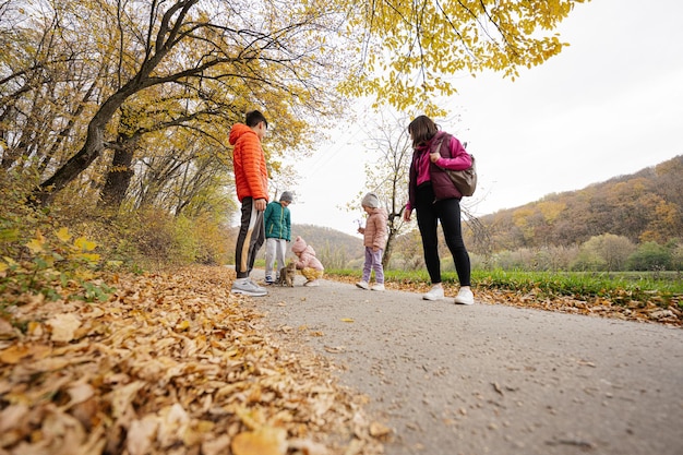 Madre con hijos y gato en un paseo por el bosque de otoño