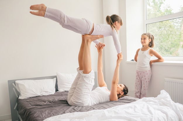 Madre con hijos haciendo ejercicio de yoga en la cama