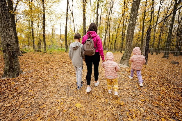 Madre con hijos en un paseo por el bosque de otoño