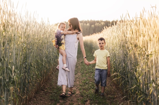 Madre con hijos con su hijo e hija caminando por un campo de trigo