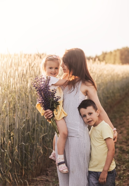 Madre con hijos con su hijo e hija caminando por un campo de trigo