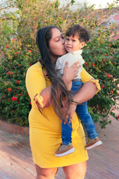 Una madre hispana sostiene amorosamente a su niño llorando en un parque.