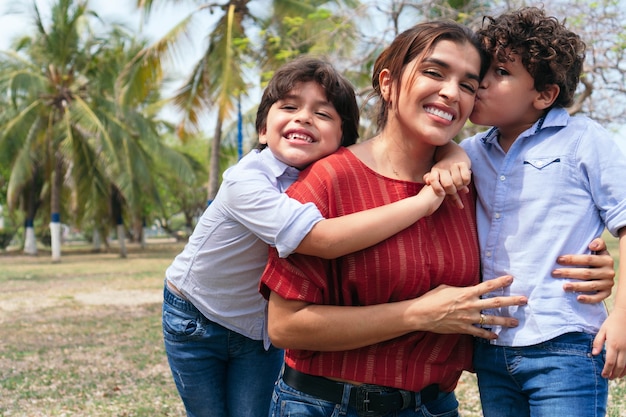 Madre hispana y sus hijos pequeños jugando en el parque.