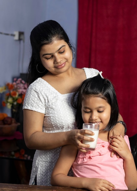 Foto una madre india asiática le da un vaso de leche a su hija