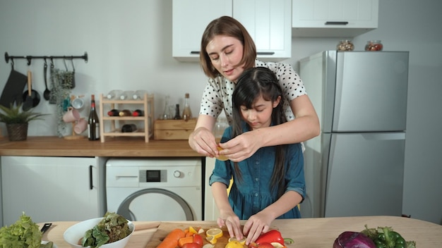 Madre inteligente y chica asiática cocinando juntos y cortando verduras Pedagogía