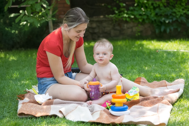 Madre joven alimentando a su bebé en un picnic en el parque