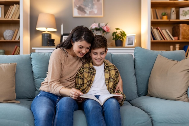 Foto madre joven y amorosa leyendo un libro a su adorable hijo pequeño sentado en el acogedor sofá en la sala de estar madre enseñando al niño niño familia pasando el fin de semana en casa juntos niños educación