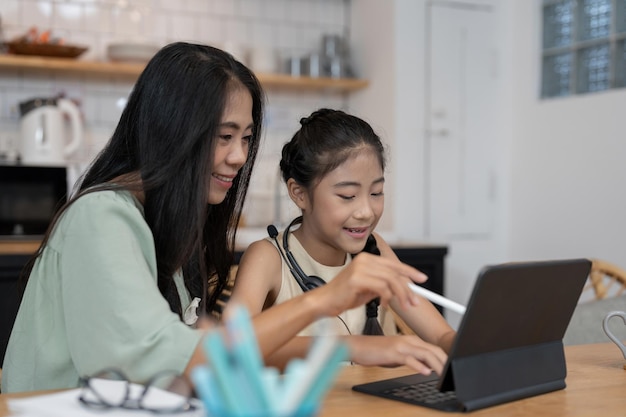 Madre joven asiática con computadora portátil que enseña a los niños a aprender o estudiar en línea en casa Concepto en línea de educación en el hogar