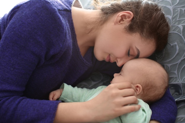 Madre joven con bebé durmiendo en casa