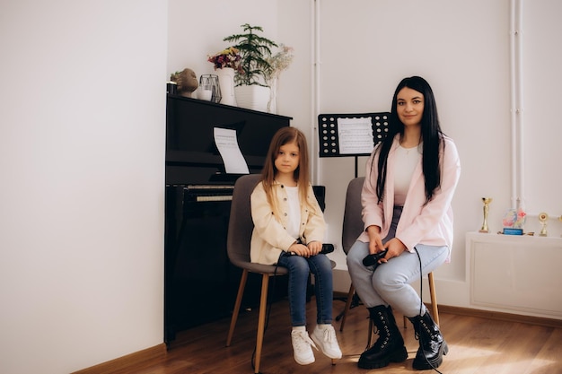 Foto madre joven cariñosa sentada en casa estudiando con su hija tartamudeando pronunciando sonidos madre amorosa padres hablan enseñando al niño discapacitado hacen ejercicios practican la pronunciación de la voz y la articulación juntos