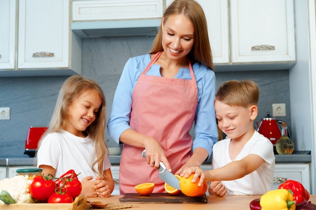 Madre joven cocinando con sus hijos en la cocina