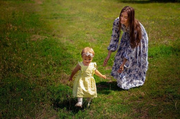 Madre joven con estilo alegre juega con su pequeña hija en el jardín verde