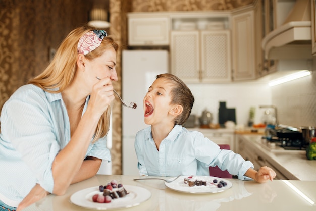 Foto madre joven con su hijo prueba pasteles de chocolate.