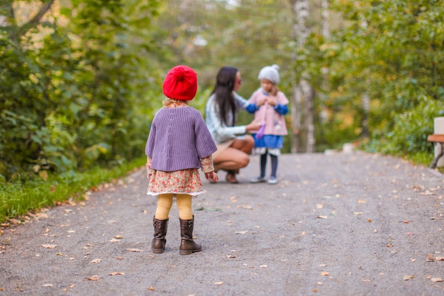 Foto madre joven con sus hijas felices adorables que se divierten oudoor en parque del otoño