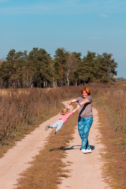 Madre juega con su hija en el campo de verano con pasto seco