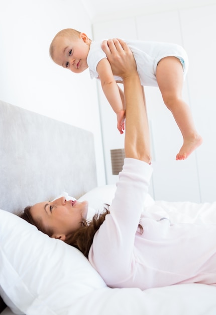 Madre jugando con bebé en la cama