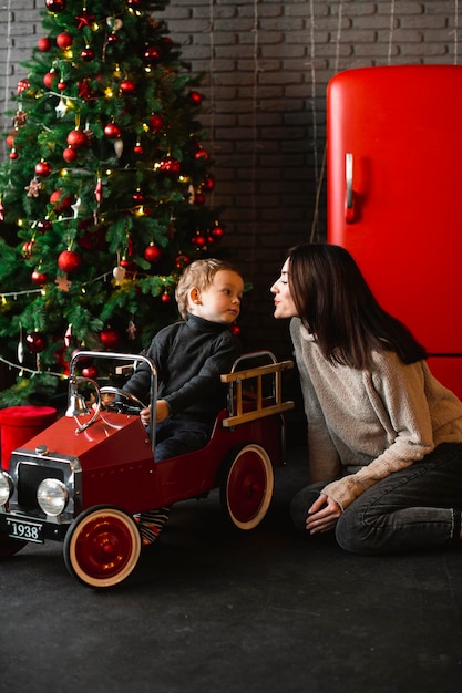 Madre jugando con el bebé junto al árbol de navidad