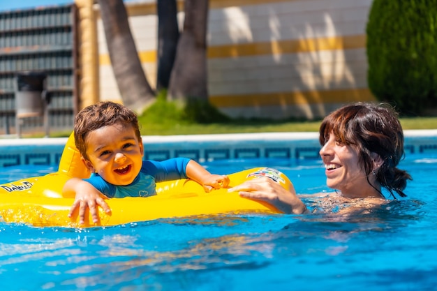 Madre jugando con su hijo con un flotador en la piscina