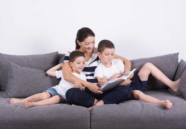 La madre lee un libro interesante con sus hijos del sofá Retrato de estudio sobre fondo blanco