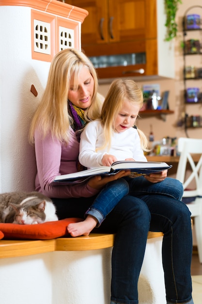 Madre leyendo el cuento nocturno a un niño en casa.