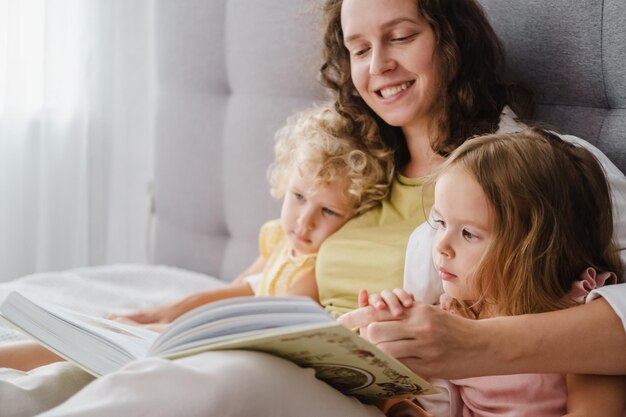 Madre leyendo un libro a sus hijas en casa