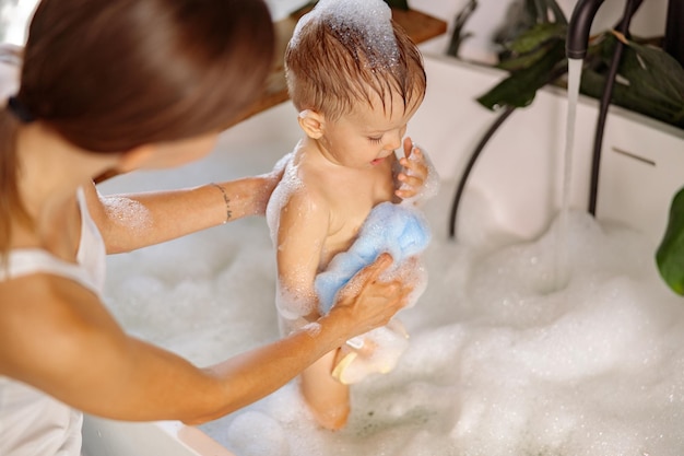Madre limpiando a su bebé con esponja