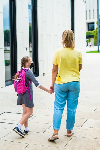 Foto la madre lleva a su hija a estudiar de la mano, caminar juntas en el parque.