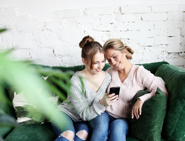 Madre madura y su hija haciendo un selfie usando un teléfono inteligente