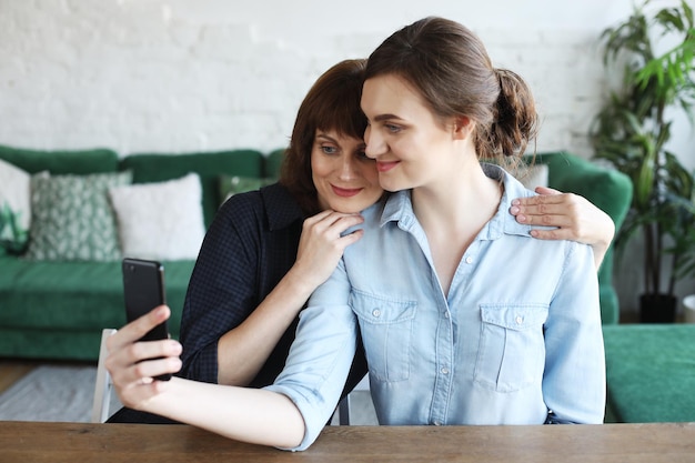 Madre madura y su hija haciendo un selfie usando un teléfono inteligente