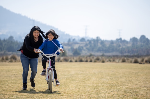 Madre mexicana enseñando a su hija a andar en bicicleta