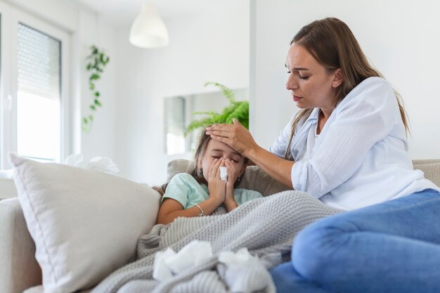 Foto madre midiendo la temperatura de su hijo enfermo. niño enfermo con fiebre alta acostado en la cama y madre sosteniendo el termómetro. mano en la frente.