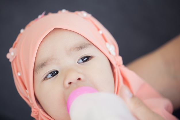 Madre musulmana alimentando a su bebé con biberón de leche.