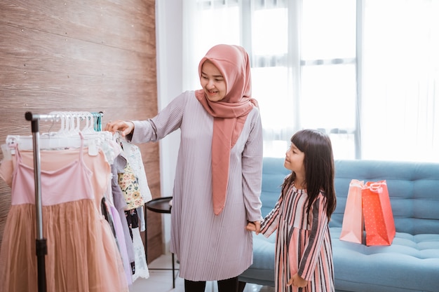 Madre musulmana de compras con su hija en la tienda de ropa boutique